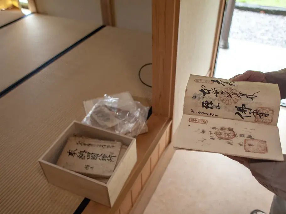 A small wooden tray holding folded old papers beside a clear bag